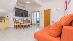 A modern living room with a sofa and a dining area with chairs and a table. - Apartments Jerkunica (Rogoznica)