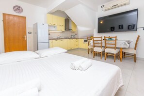 A hotel room with a bed, a kitchenette, a dining area, and a TV. - Apartments Jerkunica (Rogoznica)