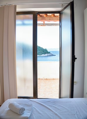 Una habitación con una cama, una toalla blanca y vistas a una playa a través de un ventanal.