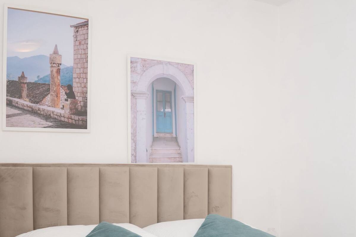 A neatly made bed with two pillows, a folded towel, and two framed pictures on the wall.