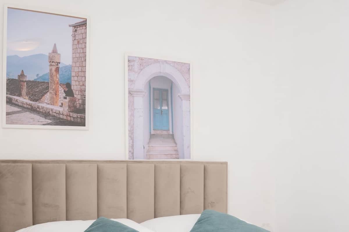 A neatly made bed with two pillows, a folded towel, and two framed pictures on the wall.