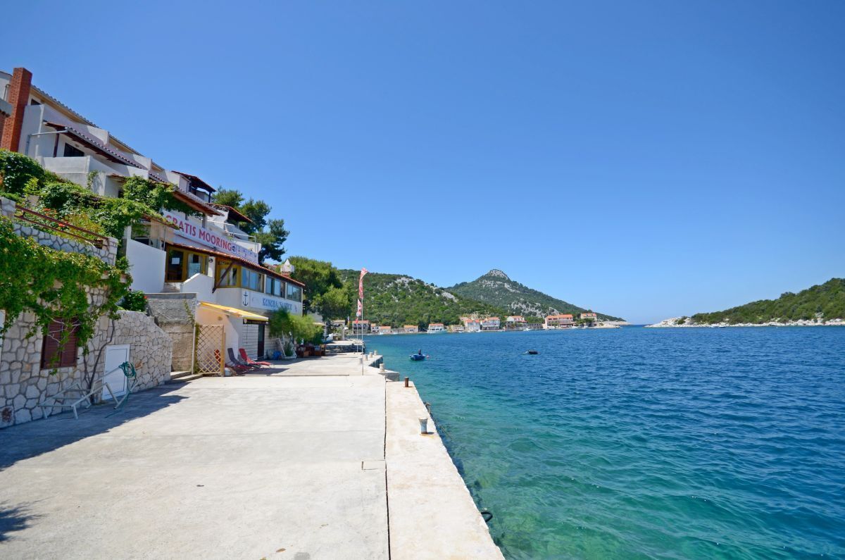 Edificio costiero con facciata in pietra, insegna di un ristorante ben visibile e vista aperta sul mare.