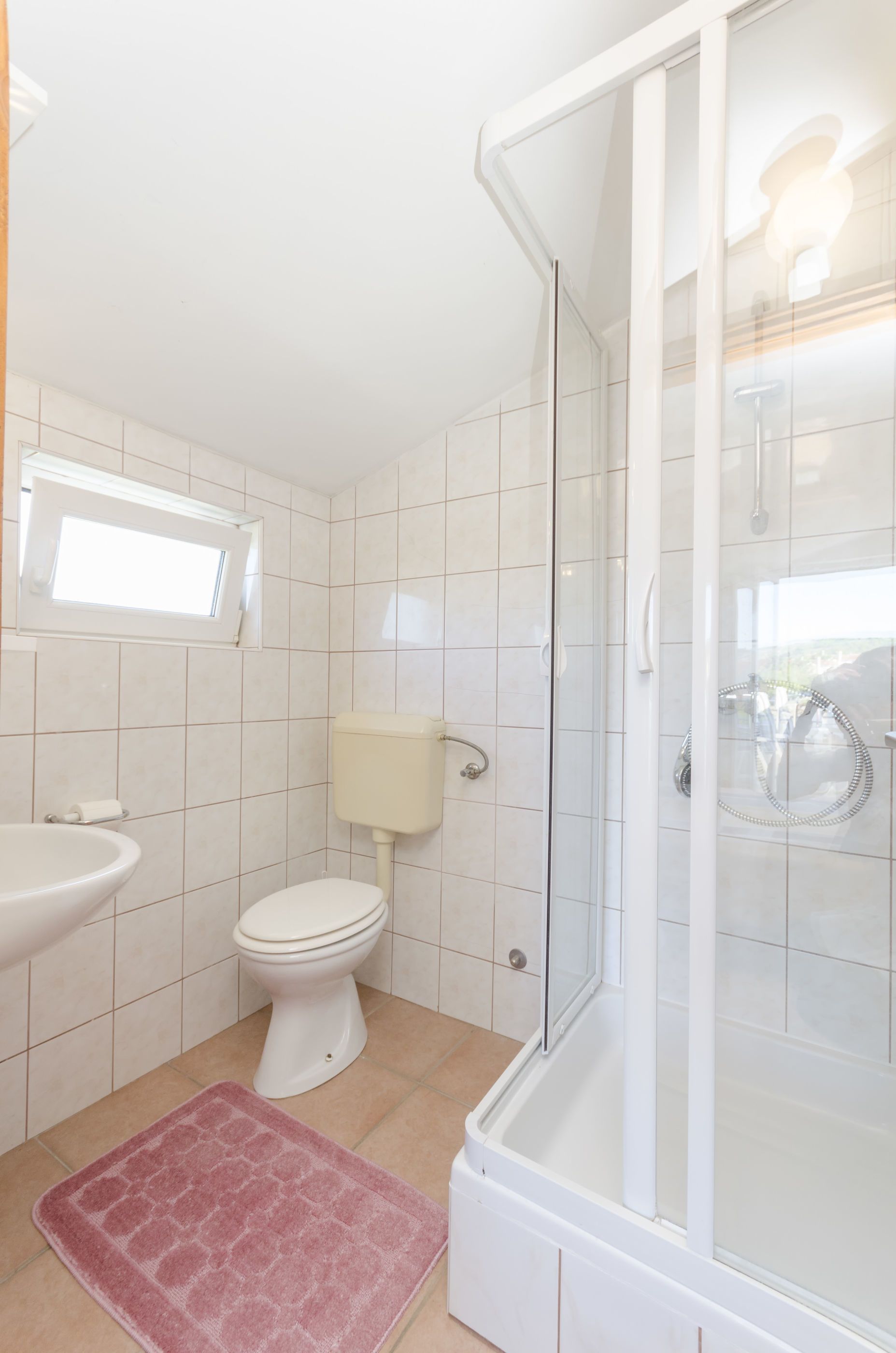 A bathroom with a toilet, sink, and shower.