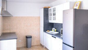 Uma cozinha moderna com armários brancos, uma geladeira de aço inoxidável, micro-ondas e pia.