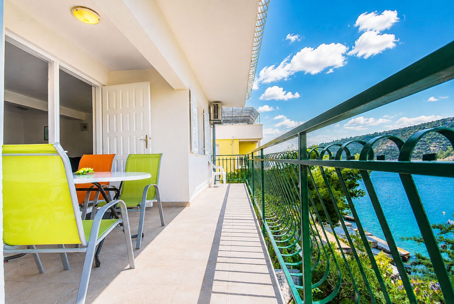 A balcony with a table and chairs, a door, and a view of a body of water.