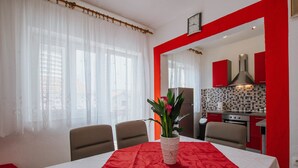A dining area with a table set for four, a vase with flowers, and a kitchen in the background. - House Josipa (Okrug Gornji)