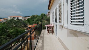 A balcony with a table and chairs, overlooking a garden and buildings. - House Josipa (Okrug Gornji)