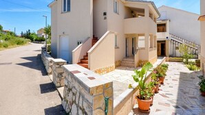 Une maison à deux étages avec un mur en pierre et une allée pavée.