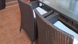 A dining area with a glass-top table and wicker chairs, connected to a kitchen and a living area with a sliding door. - Apartment Jolanka (Sukosan)