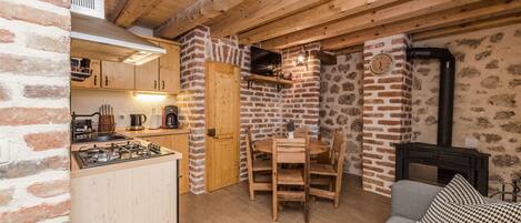 A rustic kitchen with wooden cabinets, a gas stove, and a brick wall.