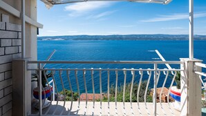 A balcony with a view of the sea, a white railing, and potted plants. - Apartments Neno (Stanici)