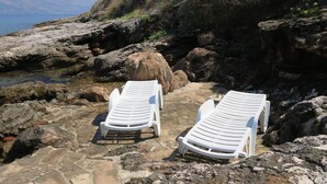 Two white lounge chairs on a rocky seaside with a view of the sea. - House Romantica (Postira)