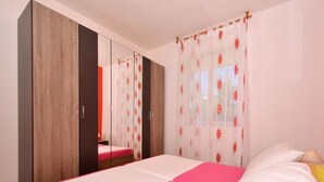 A bedroom with a bed, a wardrobe, and a window with curtains.
