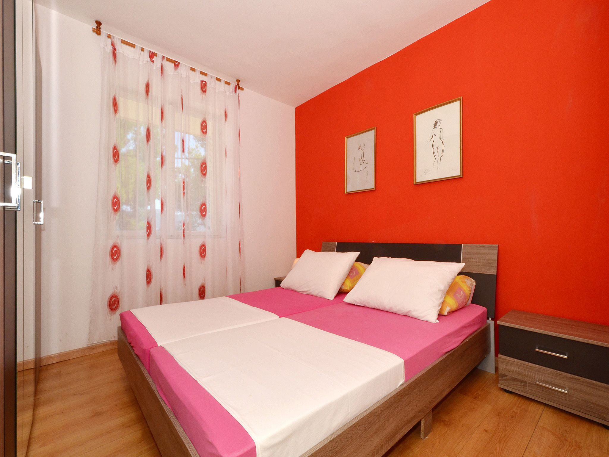 Une chambre à coucher avec un lit, une table de chevet et deux œuvres d’art encadrées accrochées au mur.