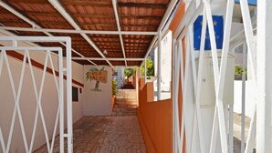 A covered walkway with a stone floor, white railings, and a mural of a palm tree.