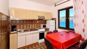 A compact kitchen with a dining area, a view of the sea, and patterned tiles.