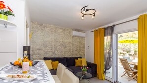 A modern living room with a sofa, a dining table, and a balcony with yellow curtains. - Apartments Apollo (Zastrazisce)