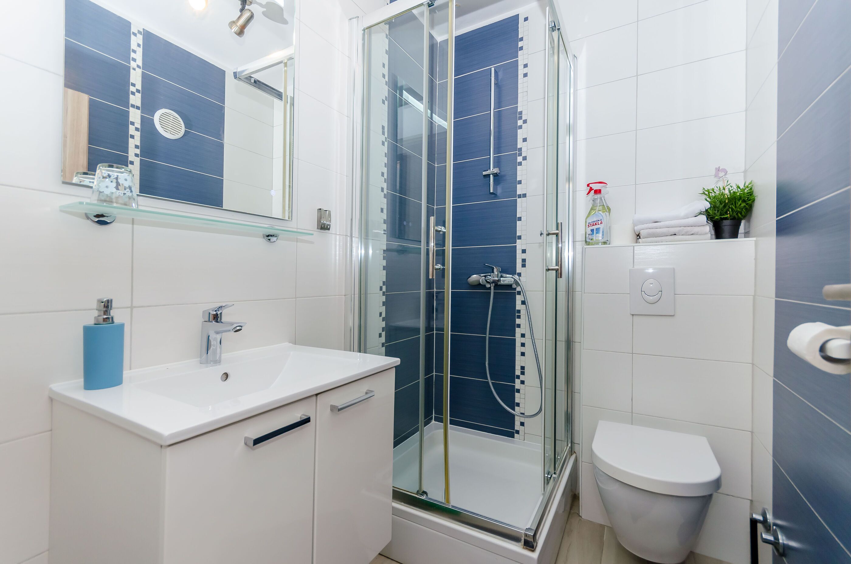 A modern bathroom with a glass-enclosed shower, a white sink, and a toilet.