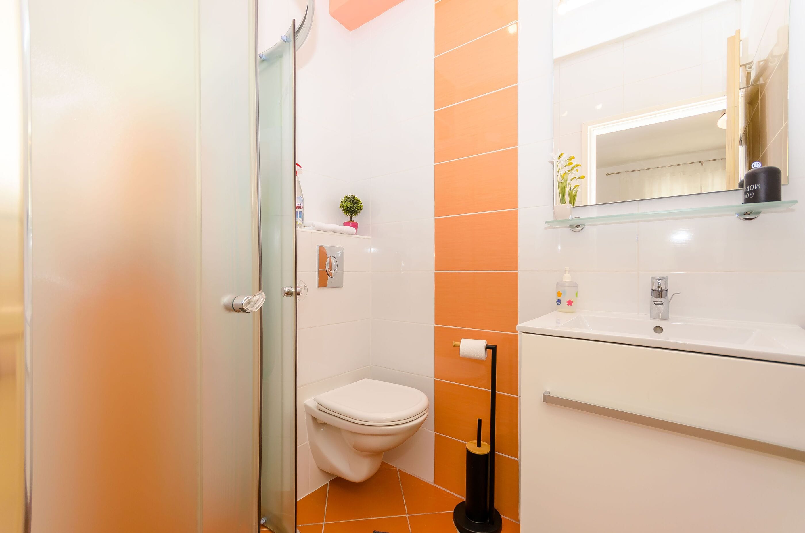 A bathroom with a toilet, sink, and glass shower enclosure.
