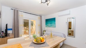 A modern room with a wooden dining table, a fruit bowl, a bottle, and a painting on the wall. - Apartments Apollo (Zastrazisce)