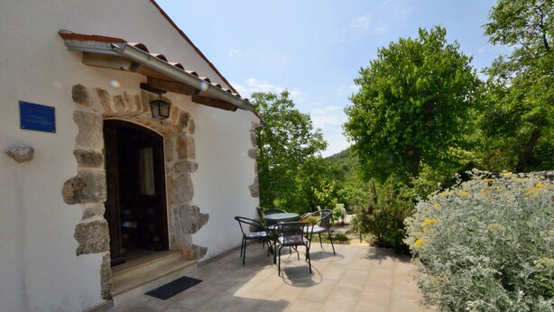 Un bâtiment en pierre doté d’un patio carrelé, d’un espace extérieur aménagé pour s’asseoir et d’un jardin.