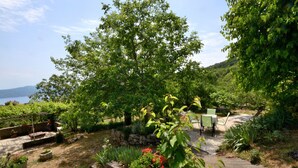 Un jardin avec un chemin en pierre, des plantes en pot et un banc.