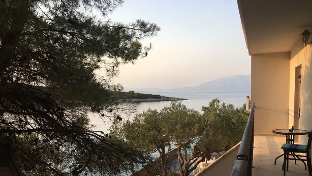 A balcony with a view of the sea and mountains, stone steps, and outdoor furniture. - House Kupina (Gdinj)