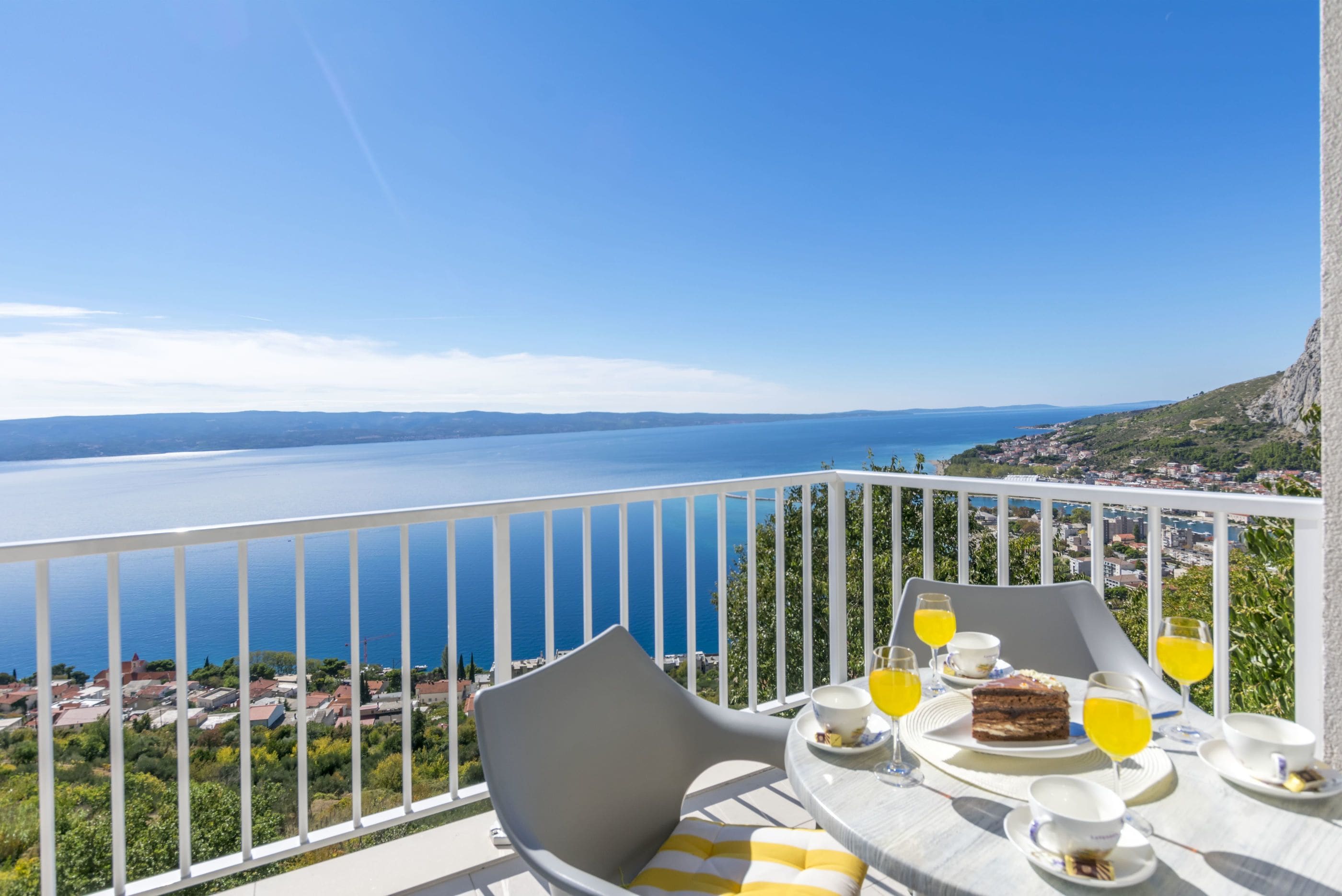 Un balcon avec une table dressée pour le petit-déjeuner, offrant une vue sur la côte.