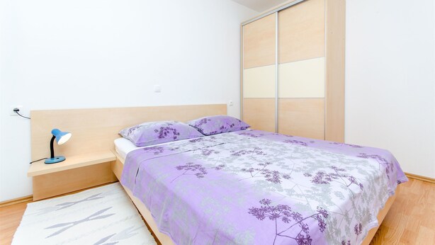 Une chambre à coucher avec un lit, une table de chevet, une lampe et une porte de placard coulissante.