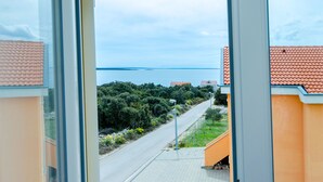 A coastal road with houses on one side and a view of the sea. - Apartments Andrea (Mandre)