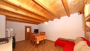 A dining area with a table and chairs, a red sofa, and a television in the background. - House Paklenica Stone Beauty (Starigrad - Paklenica)