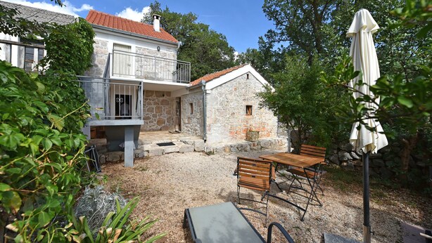 A stone house with a balcony, a patio with a table and benches, and a white umbrella. - House Paklenica Stone Beauty (Starigrad - Paklenica)