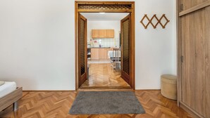 A hallway leading to a kitchen with wooden cabinets and a herringbone floor pattern. - Apartment Vinko (Starigrad - Paklenica)