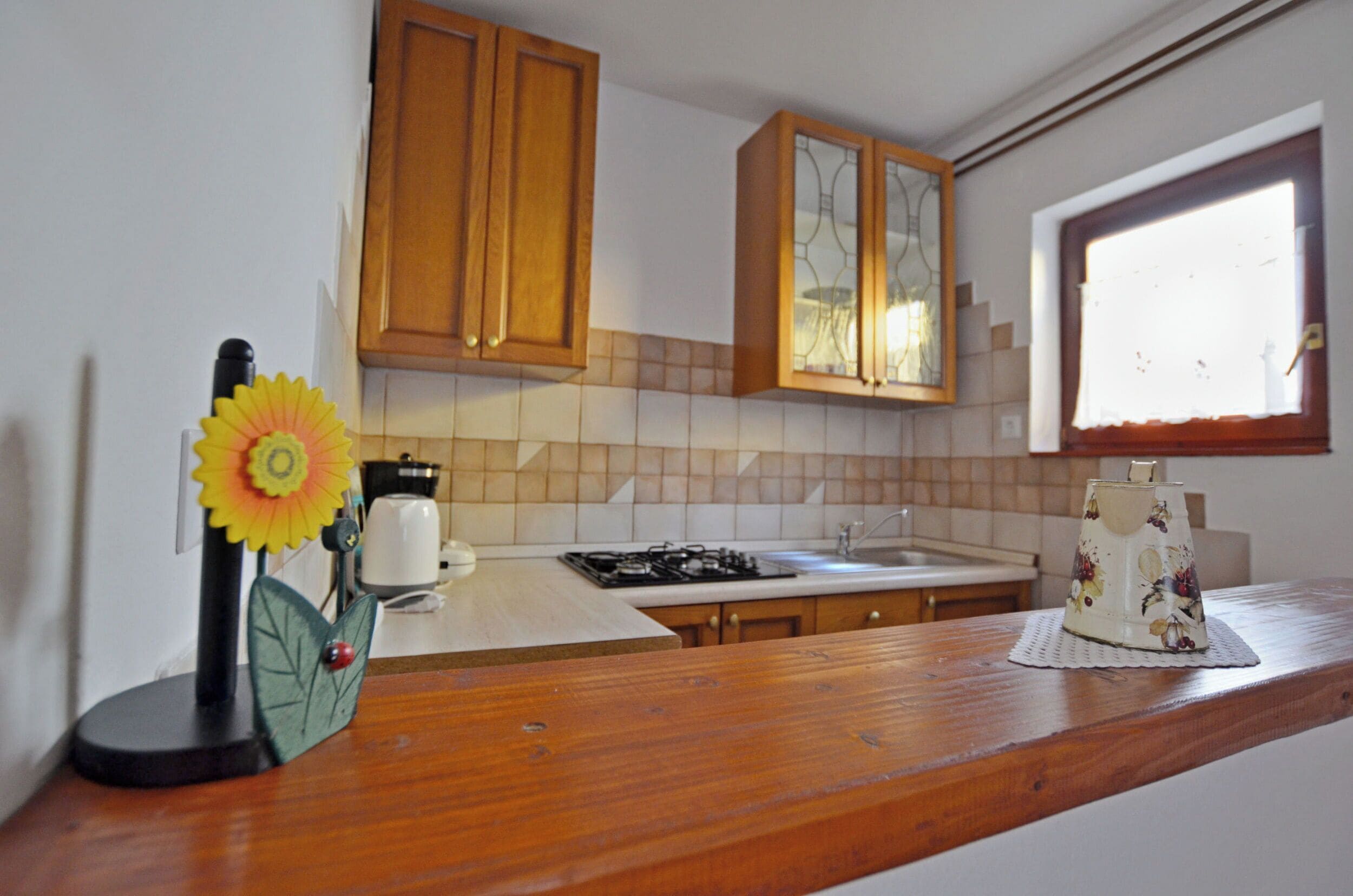 A kitchen with wooden cabinets, a tiled backsplash, a stove, and a window with blinds.