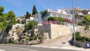 Un barrio residencial en una ladera, con muros de piedra, una carretera y edificios con balcones.