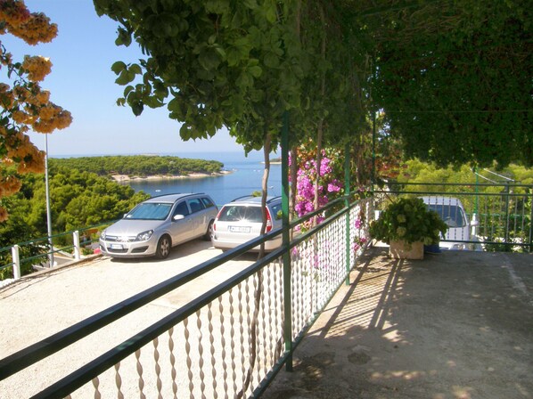 A balcony with a view of the sea and parked cars. - Apartment Dijo I (Primosten)