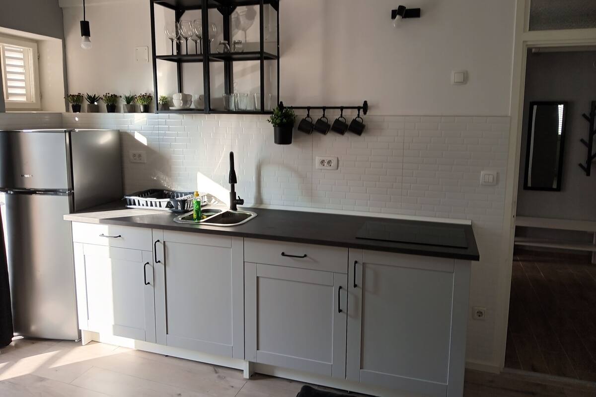 Una cuina moderna amb armaris blancs, un frigorífic d'acer inoxidable i un taulell negre.