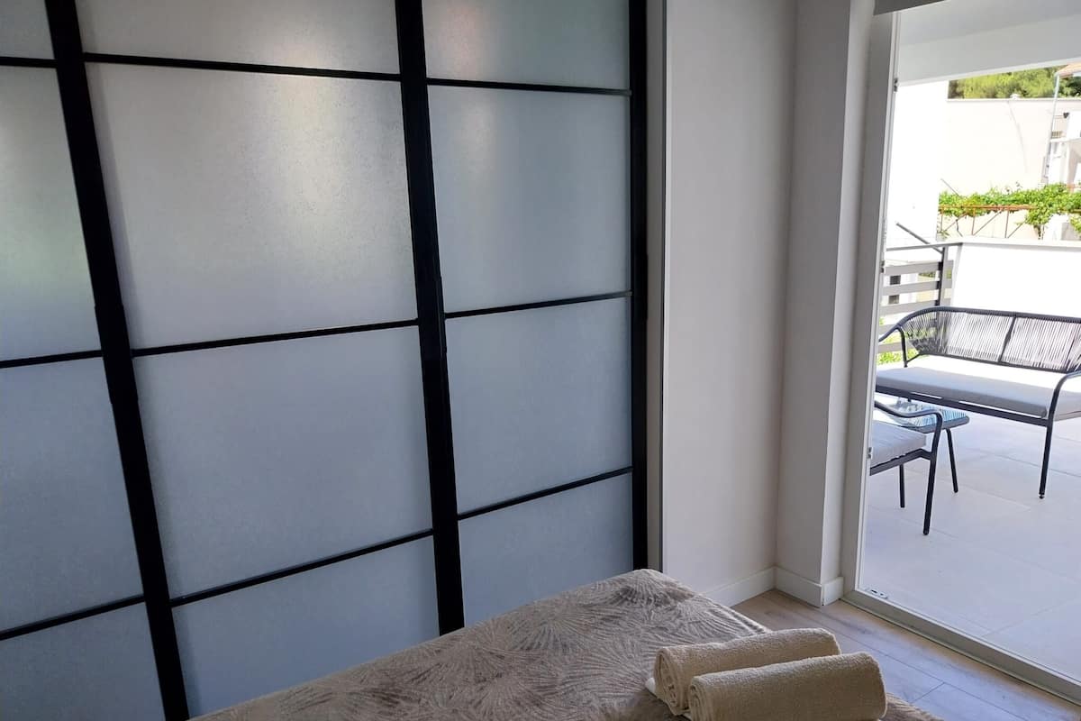 Habitació amb una porta corredissa de vidre que dona a una zona d'estar exterior amb taula i cadires.