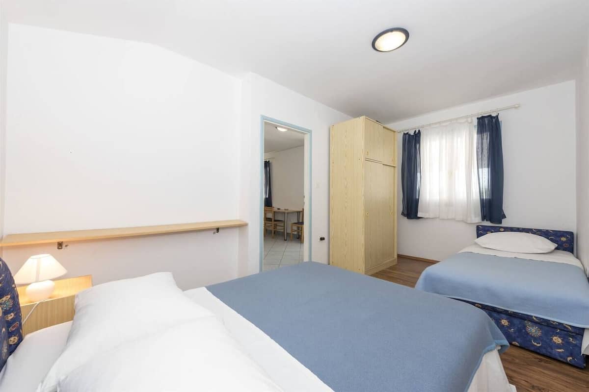 Habitació d'hotel amb dos llits, un armari de fusta, escriptori i una cadira.