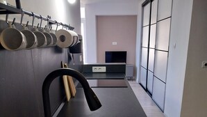 Eine moderne Küche mit Spüle aus Edelstahl, einem schwarzen Wasserhahn und einer Wandhalterung für Töpfe.
