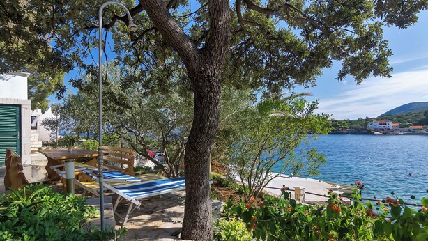 A stone pathway leading to a wooden deck by a lake, with a hammock and a lamp post. - House Sea Rose (Zastrazisce)