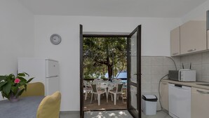 A compact kitchen with a dining area, a view of trees and water, and a clock on the wall. - House Sea Rose (Zastrazisce)