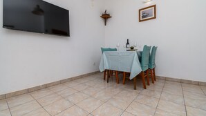 Ein Essbereich mit einem Tisch für vier Personen, einem an der Wand montierten Flachbildfernseher und einem kleinen dekorativen Gegenstand an der Wand.