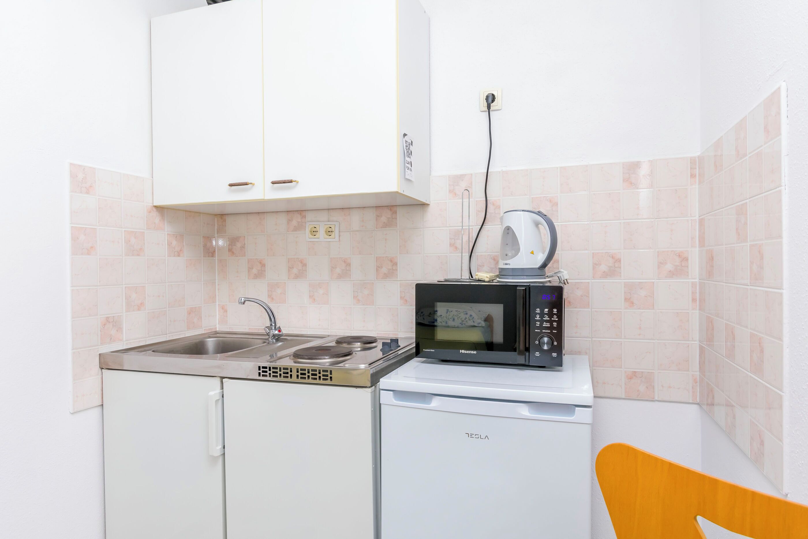 A compact kitchen with a sink, a microwave, and a small white dishwasher.