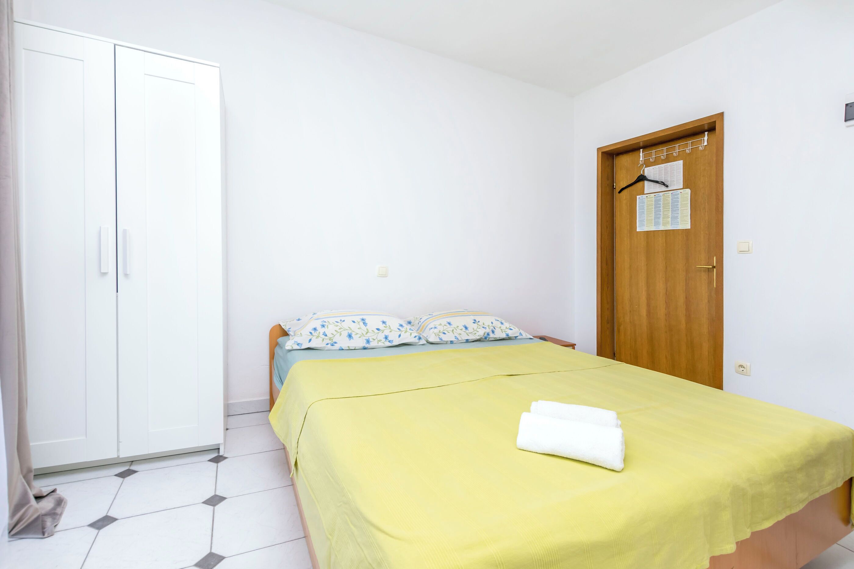 A bedroom with a bed, a wardrobe, and a door with a calendar.