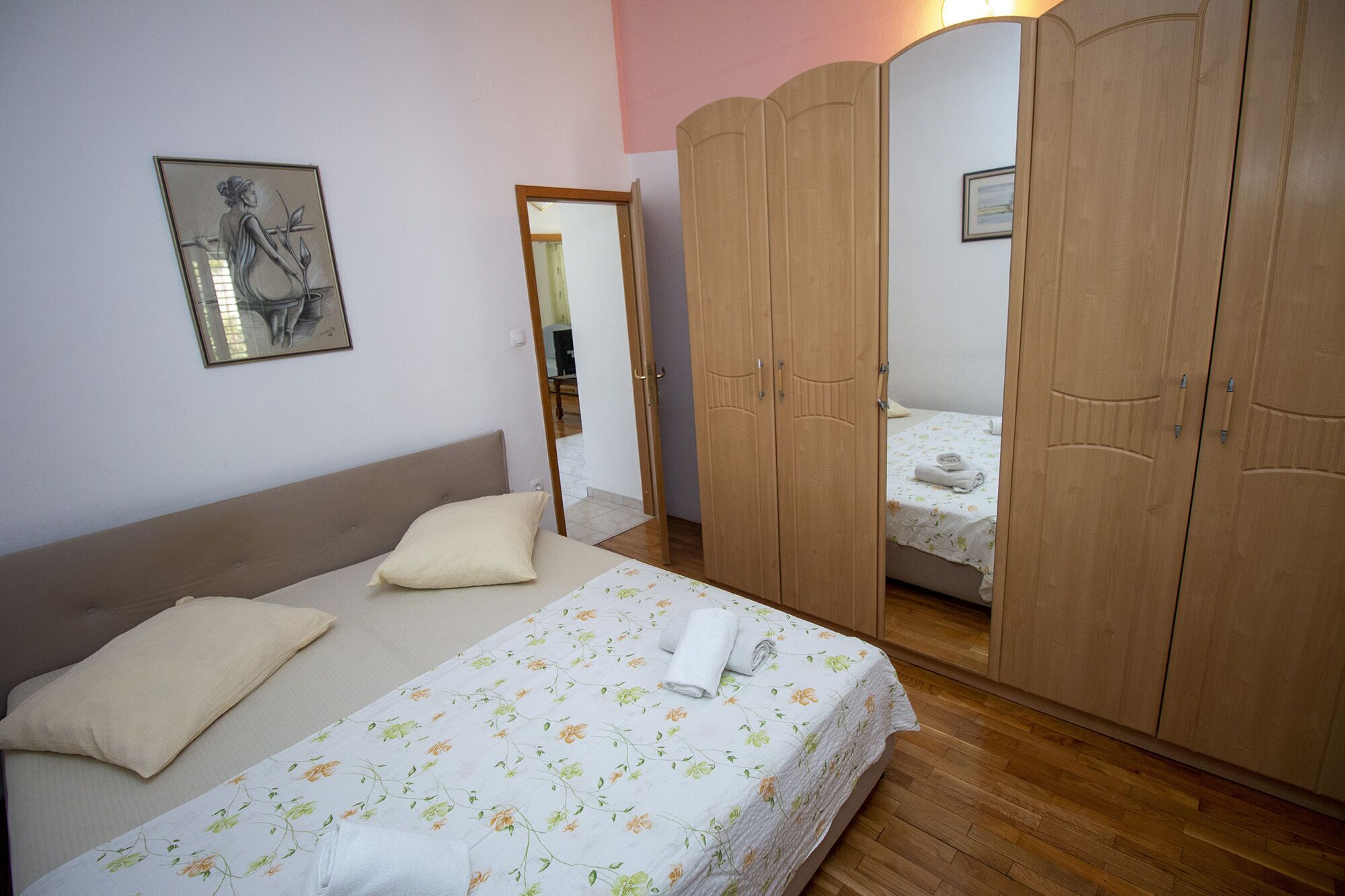 A bedroom with a bed, a wardrobe, and a mirror.