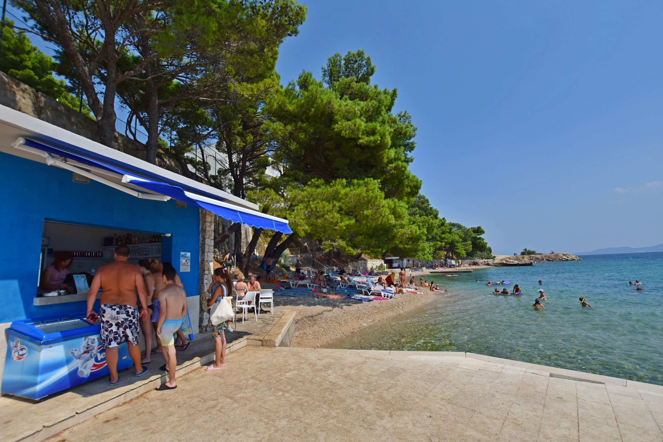 A beachside café with outdoor seating and a view of the sea.