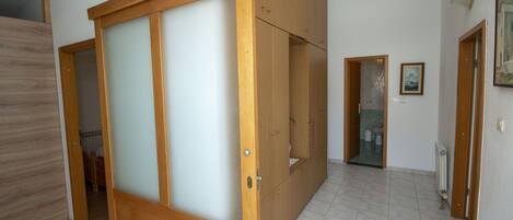 Una habitación con una puerta corredera de madera, suelo de baldosas y un baño pequeño a la vista.