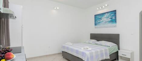 Un dormitorio con cama, mesita de noche, un cuadro y un frutero.