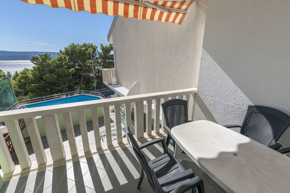 Un balcó amb vista a una piscina, una taula i dues cadires.